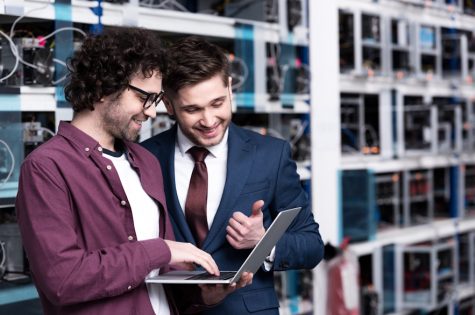 happy young businessman and computer engineer working together at ethereum mining farm