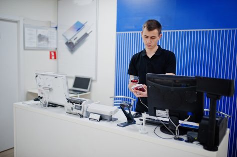 Seller man mobile phone professional consultant in tech store or shop works at the cashier.